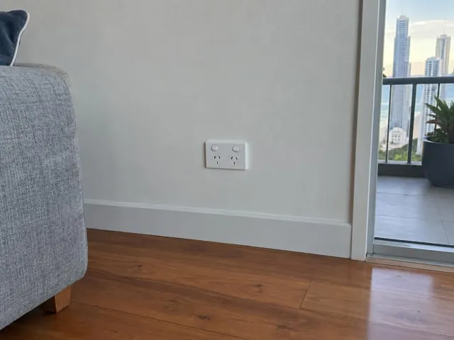 Double power point on a white wall beside timber flooring and a balcony opening in Surfers Paradise